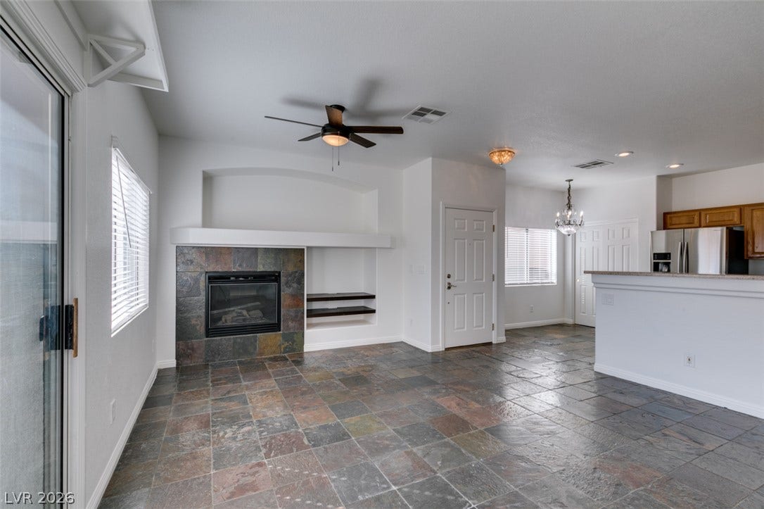 3612 Indigo Flower Street, #2, North Las Vegas, NV 89084 Natural stone tile floors complement the stone fireplace surround in an open living space.