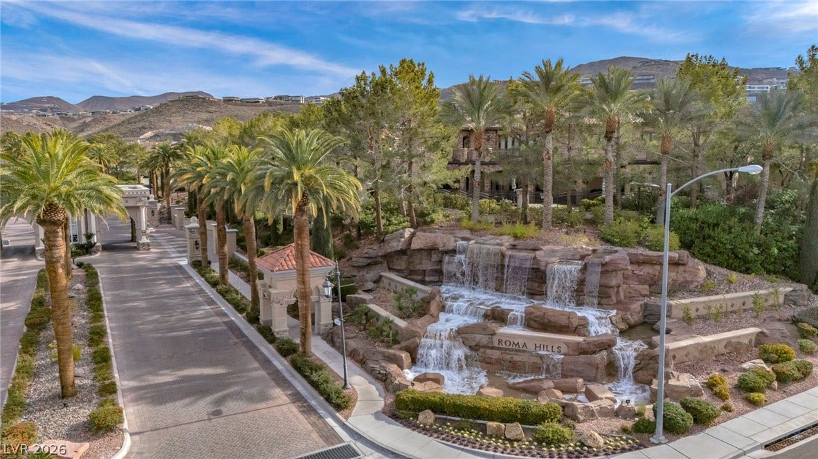 1793 Anelli Court, Henderson, NV 89012 An elegant stone waterfall monument anchors the gated entry path under desert peaks.