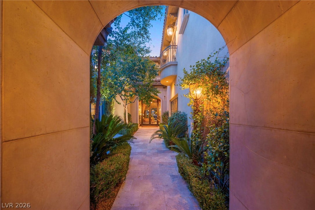 1793 Anelli Court, Henderson, NV 89012 An elegant stone archway frames the lushly landscaped courtyard and paved path leading to the entrance.