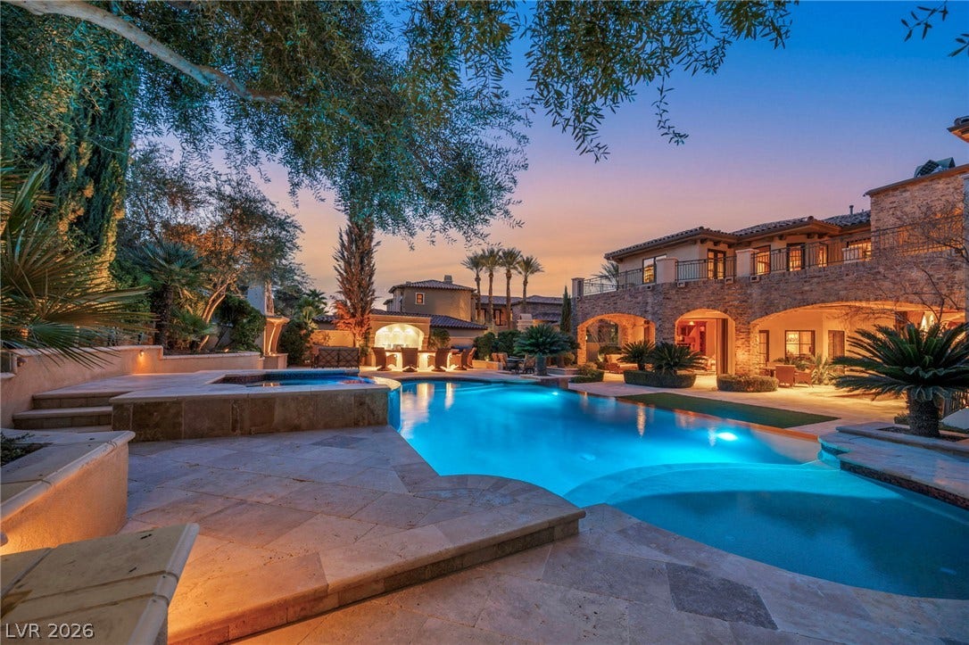 1793 Anelli Court, Henderson, NV 89012 Lush tropical landscaping frames a glistening swimming pool and stone-accented rear patio at twilight.