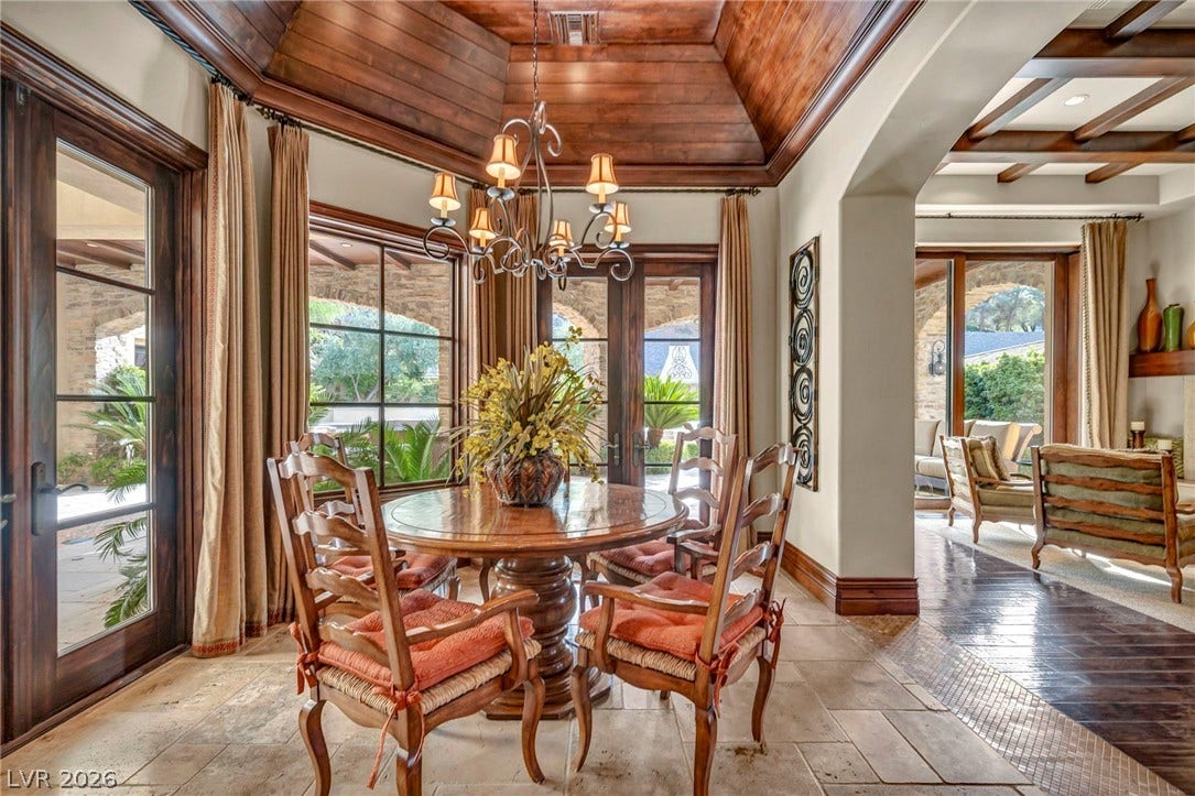 1793 Anelli Court, Henderson, NV 89012 Rich wood plank ceilings and classic stone tile flooring elevate this elegant dining space.
