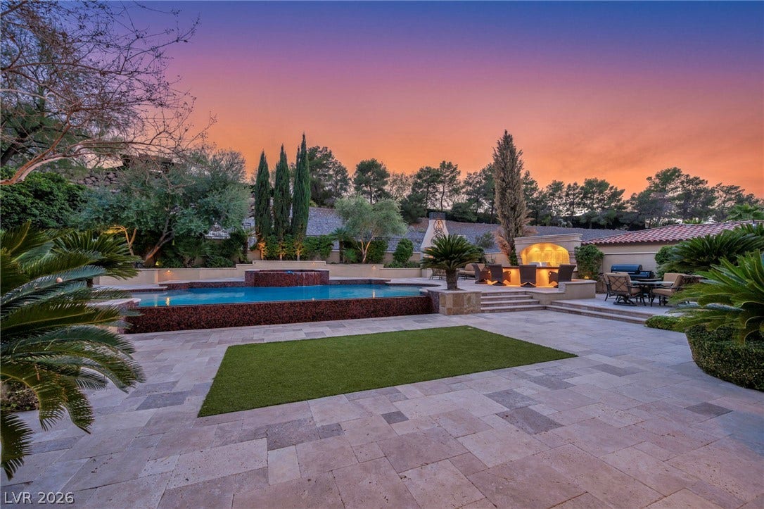 1793 Anelli Court, Henderson, NV 89012 Stone pavers frame a geometric pool and custom outdoor kitchen set against a twilight sky.