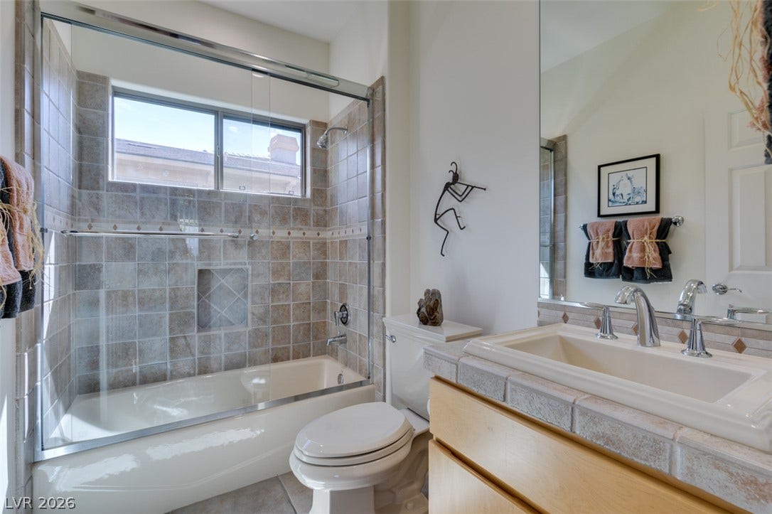 51 E Braelinn Drive, Henderson, NV 89052 Earth-toned tiles border the bathtub and vanity sink in this comfortable bathroom.