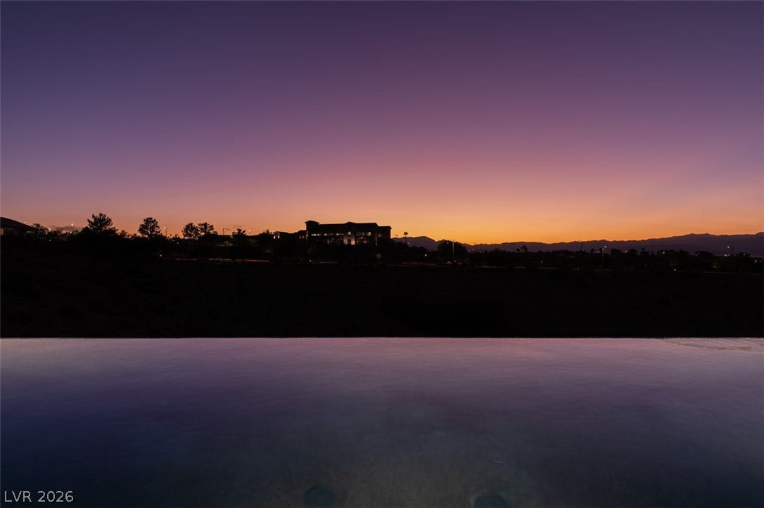 51 E Braelinn Drive, Henderson, NV 89052 Distant mountains frame the horizon beyond a serene infinity pool at sunset.