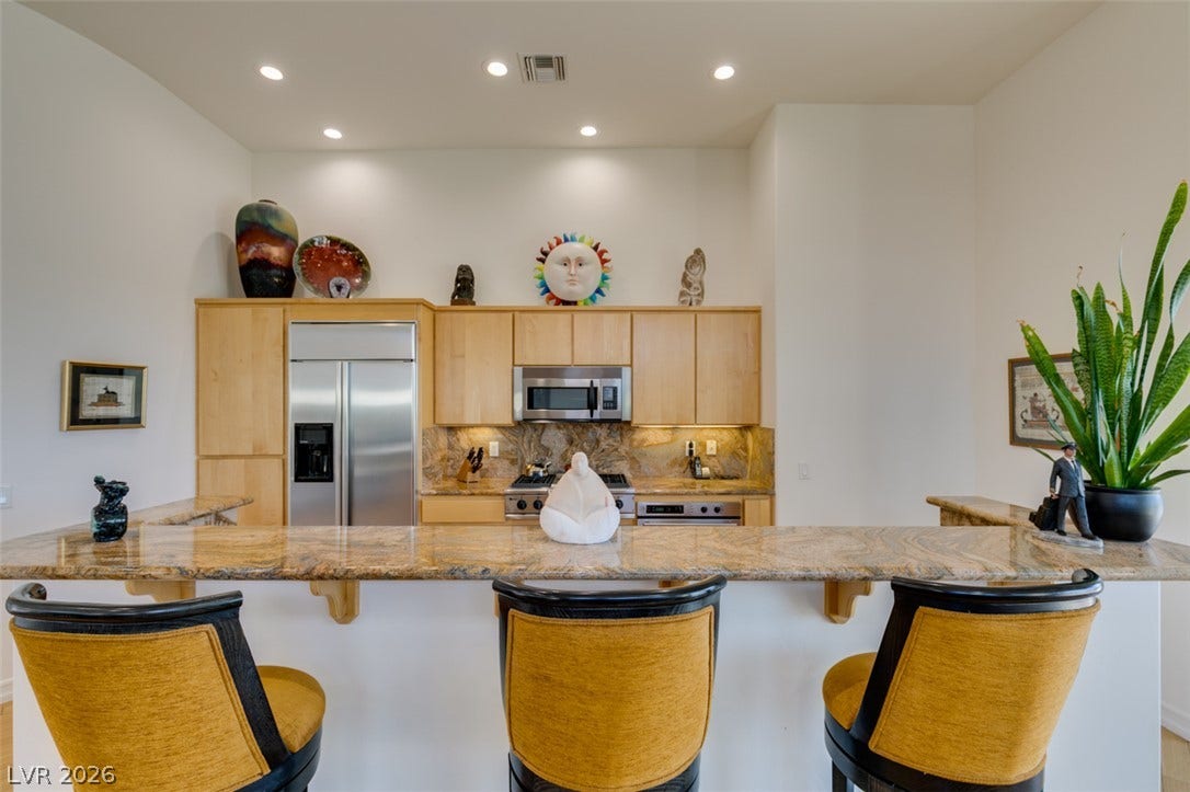 51 E Braelinn Drive, Henderson, NV 89052 Gleaming stone countertops and matching backsplash accent this modern kitchen workspace.