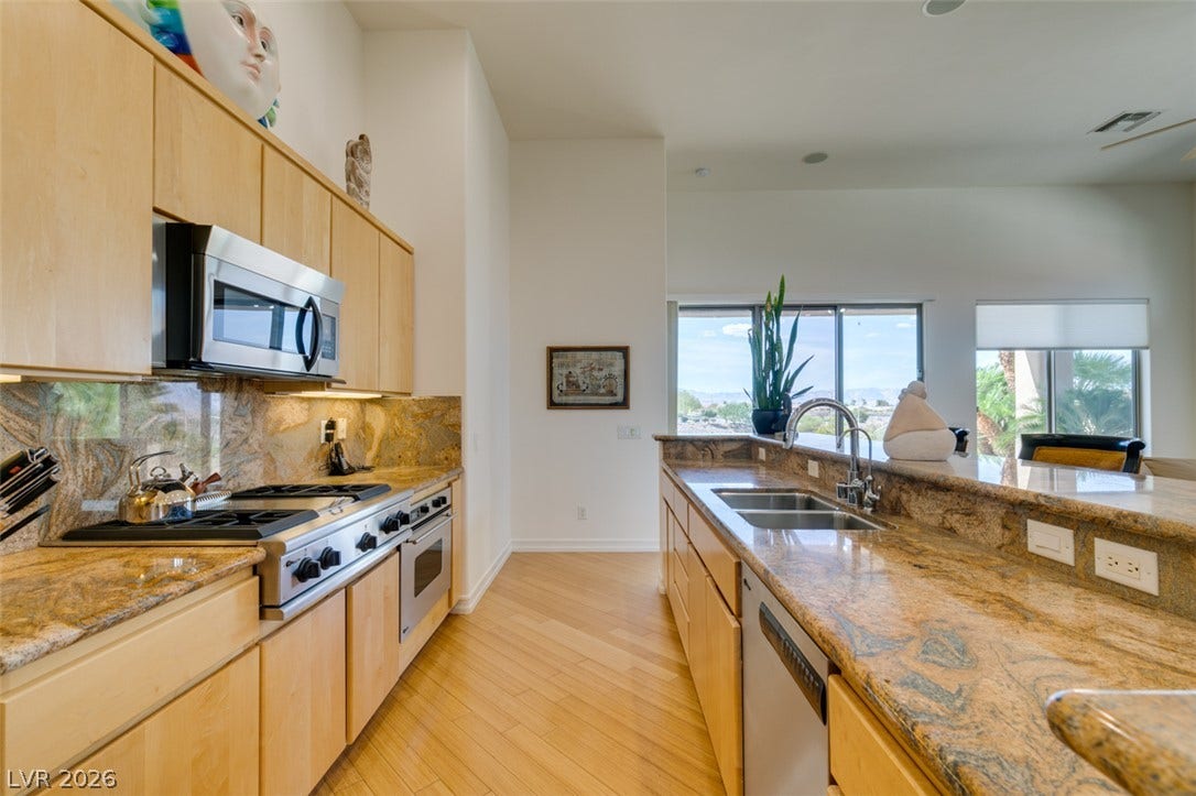 51 E Braelinn Drive, Henderson, NV 89052 Gleaming granite countertops and rich wood flooring anchor this open and airy kitchen space.