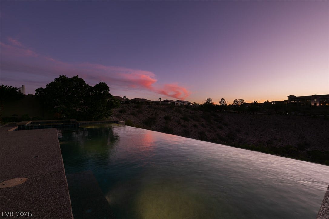 51 E Braelinn Drive, Henderson, NV 89052 An infinity pool overlooks a desert landscape under vibrant evening skies.