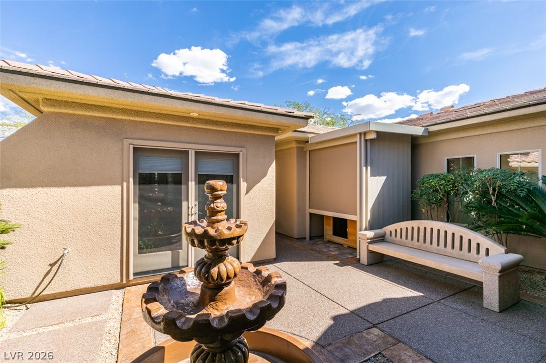 51 E Braelinn Drive, Henderson, NV 89052 An inviting stone courtyard features a classical fountain under clear blue skies.