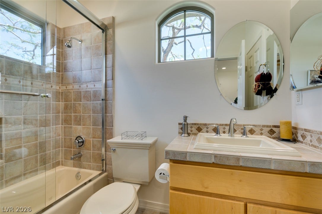51 E Braelinn Drive, Henderson, NV 89052 Natural light streams through an arched window, illuminating the tiled shower and vanity area.