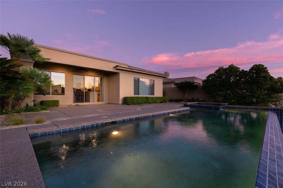 51 E Braelinn Drive, Henderson, NV 89052 A pristine swimming pool frames this modern backyard retreat under a vibrant evening sky.