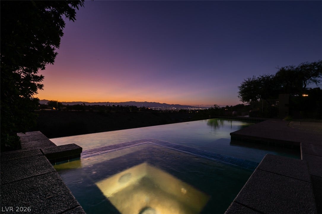 51 E Braelinn Drive, Henderson, NV 89052 Distant city lights and mountain silhouettes frame the peaceful infinity pool during twilight.