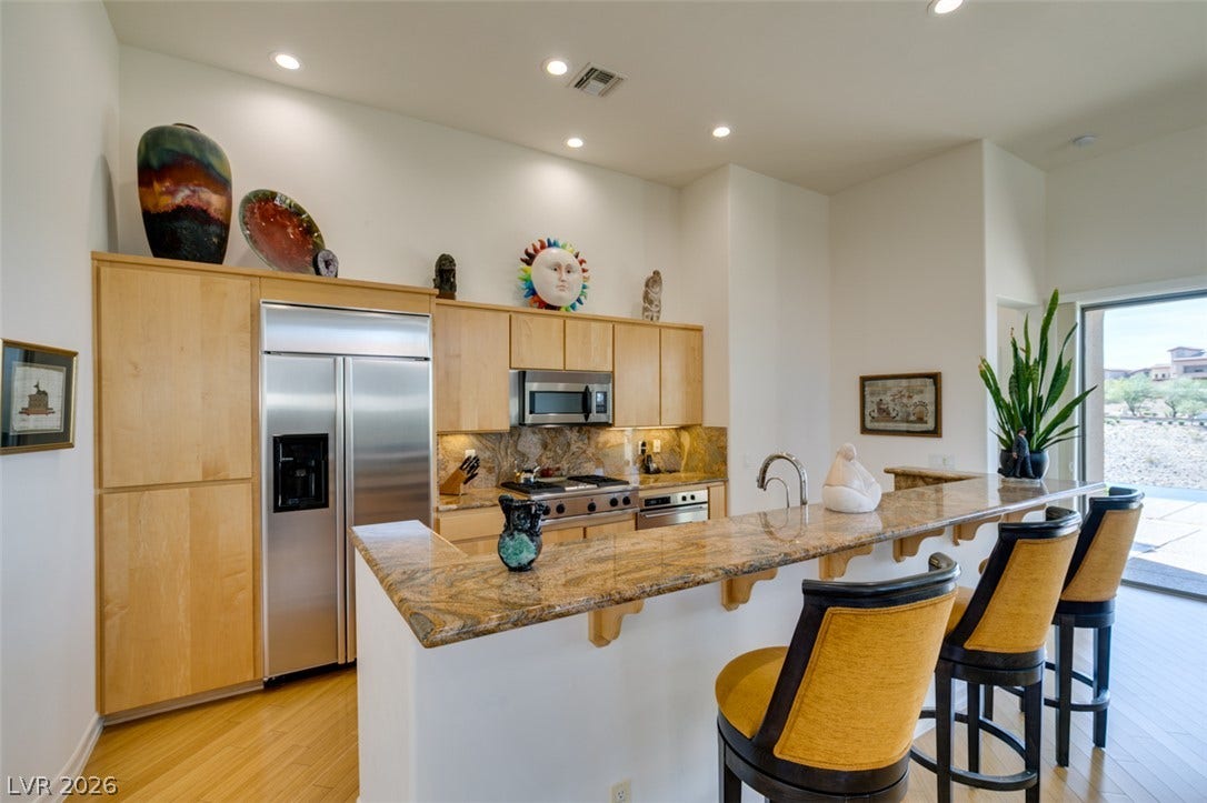 51 E Braelinn Drive, Henderson, NV 89052 Polished stone countertops pair with light wood cabinetry in an airy kitchen setting.
