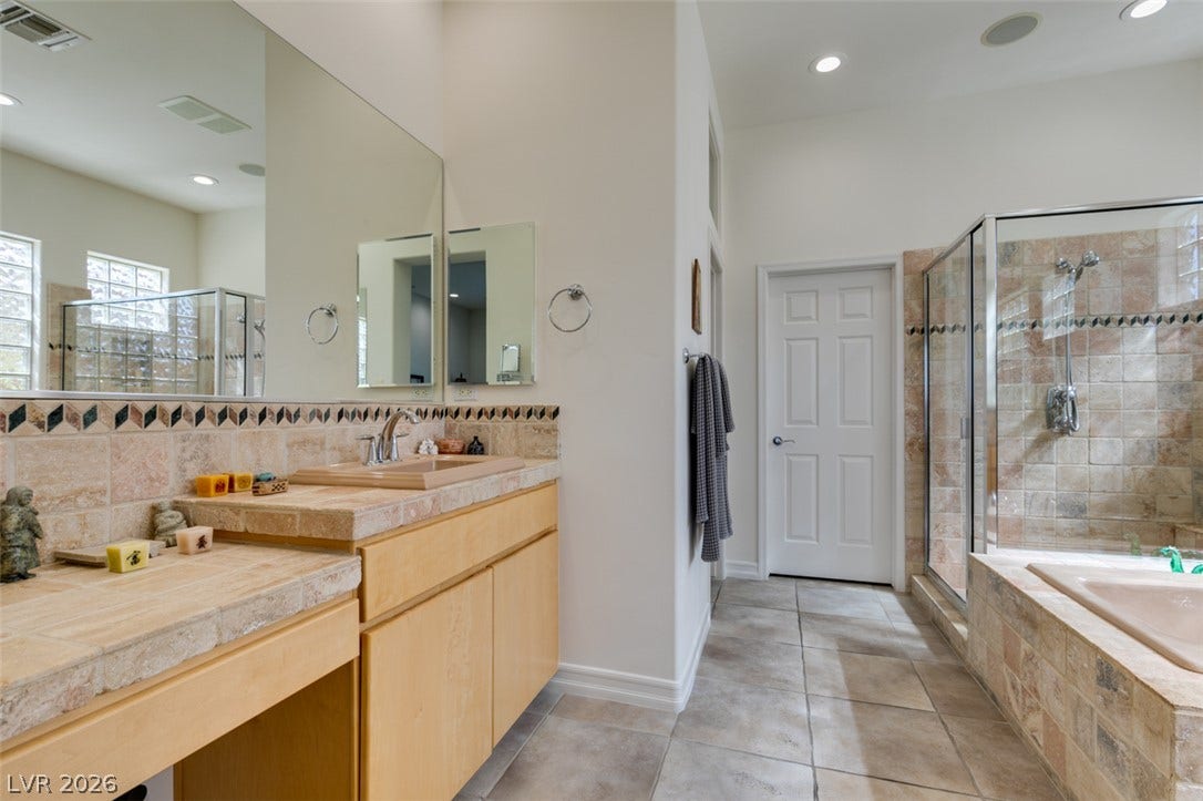 51 E Braelinn Drive, Henderson, NV 89052 Earth-toned stone tile finishes bring natural texture to this spacious primary bath.
