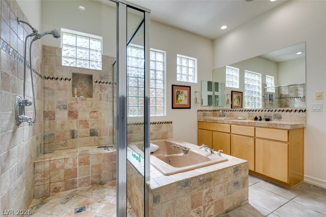 51 E Braelinn Drive, Henderson, NV 89052 Natural stone tile work runs from the walk-in shower to the soaking tub surround.