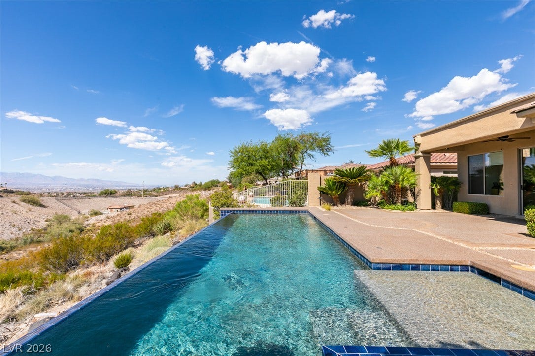 51 E Braelinn Drive, Henderson, NV 89052 An inviting infinity pool overlooks far-reaching desert valley views under wide blue skies.