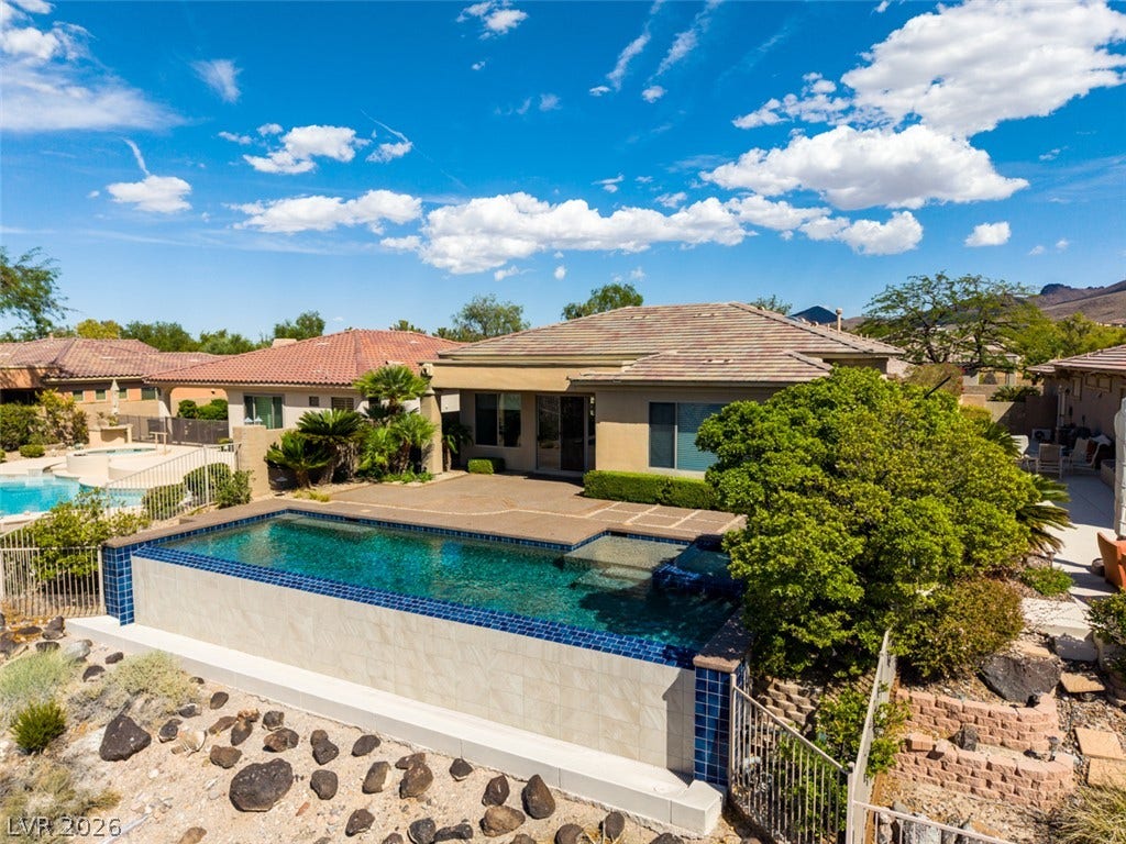 51 E Braelinn Drive, Henderson, NV 89052 An inviting backyard oasis features a modern swimming pool against a scenic mountain backdrop.