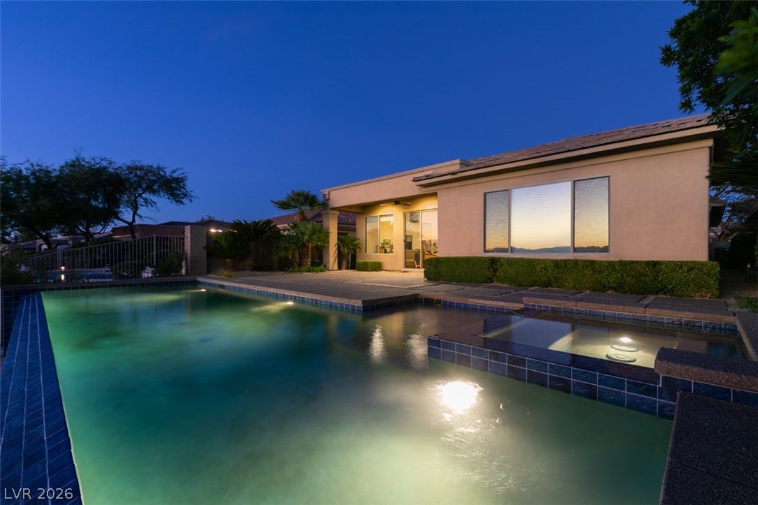 51 E Braelinn Drive, Henderson, NV 89052 An inviting backyard oasis showcases a sparkling pool and spa set against a stucco exterior.