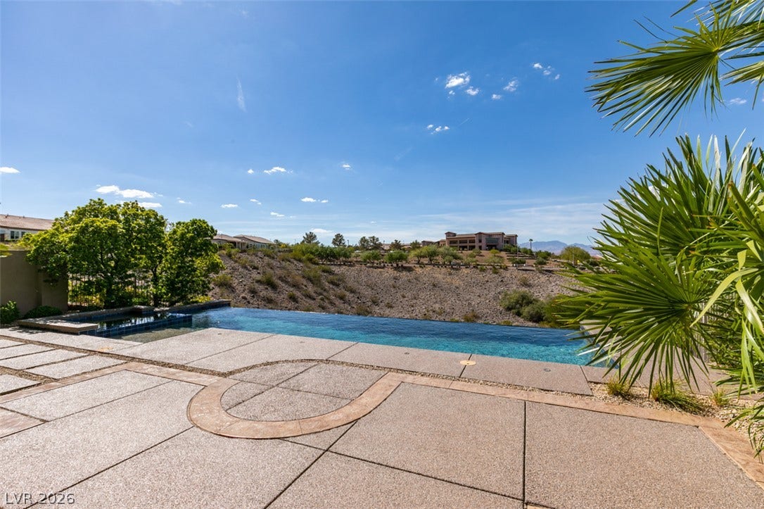 51 E Braelinn Drive, Henderson, NV 89052 An inviting infinity pool overlooks a desert landscape under a clear blue sky.