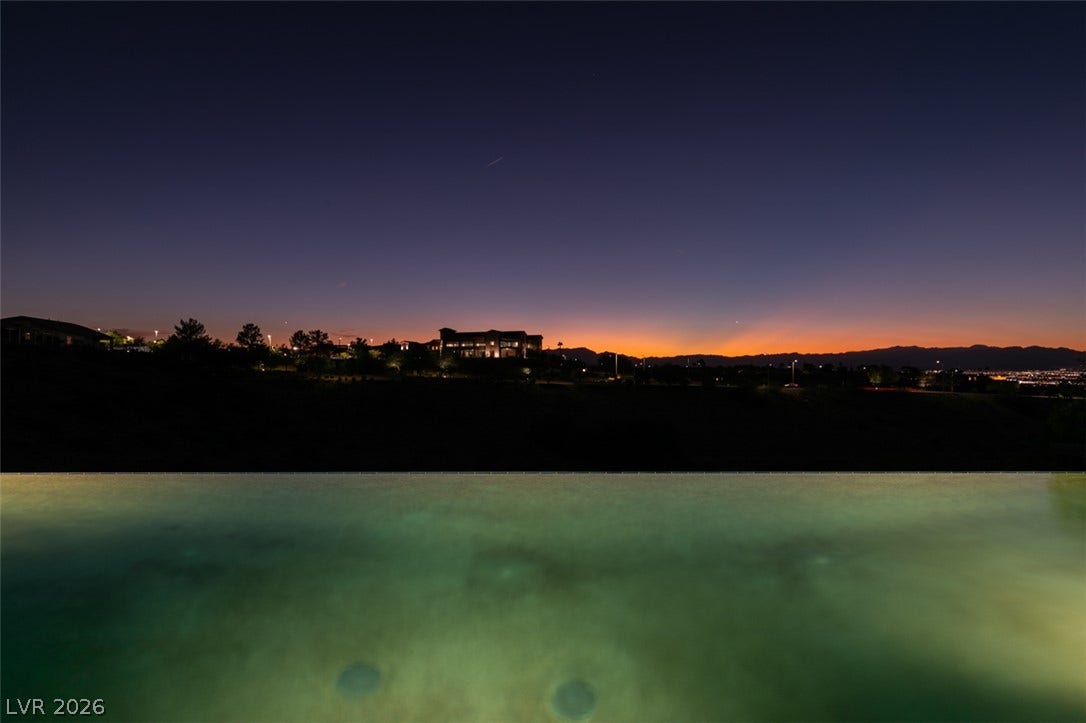 51 E Braelinn Drive, Henderson, NV 89052 Dramatic sunset skies frame distant mountain silhouettes beyond a tranquil infinity pool.