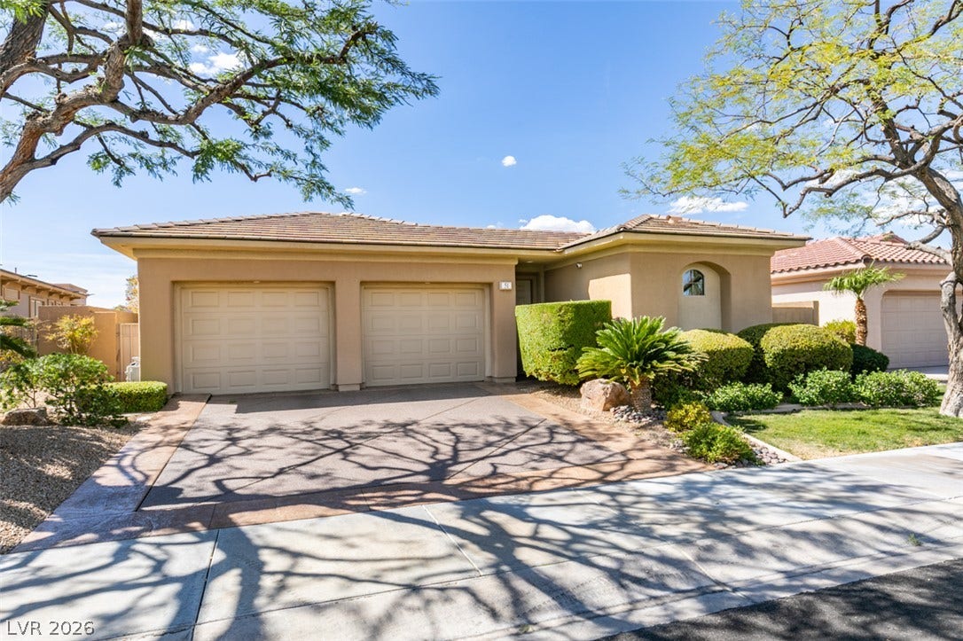 51 E Braelinn Drive, Henderson, NV 89052 Mature trees shade the driveway of this single-story home with a two-car garage.