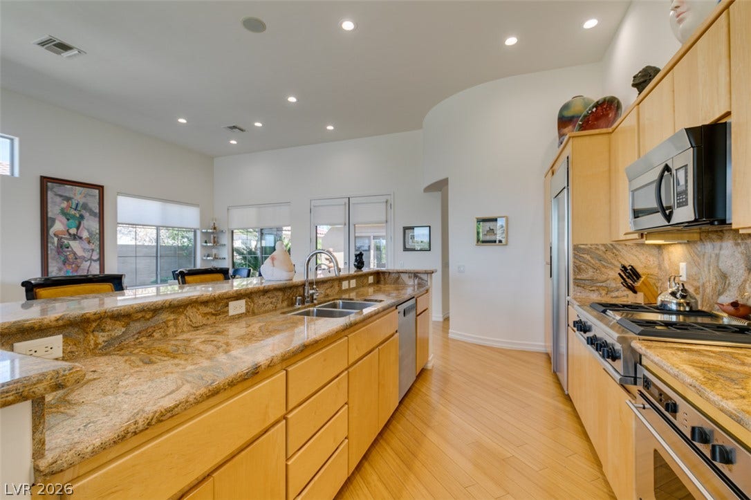 51 E Braelinn Drive, Henderson, NV 89052 Gleaming hardwood floors and rich stone countertops define this spacious, modern kitchen workspace.