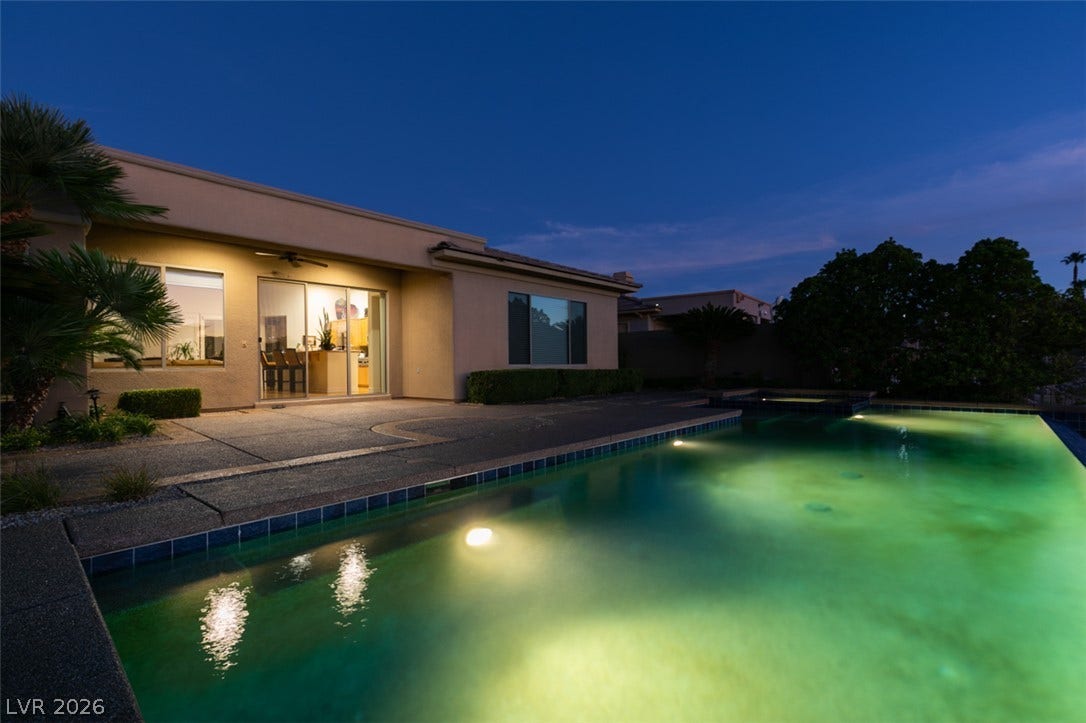 51 E Braelinn Drive, Henderson, NV 89052 An inviting backyard pool glows under the twilight sky adjacent to the stucco exterior.
