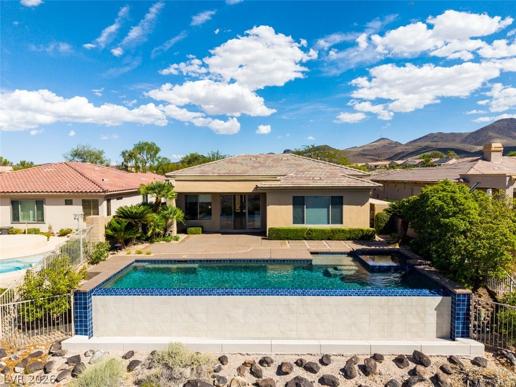 51 E Braelinn Drive, Henderson, NV 89052 An inviting backyard oasis features a modern swimming pool against a backdrop of desert mountains.