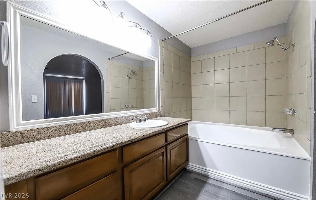 2700 N Rainbow Boulevard, #2137, Las Vegas, NV 89108 A spacious vanity with stone countertops stands adjacent to a tiled tub and shower combination.