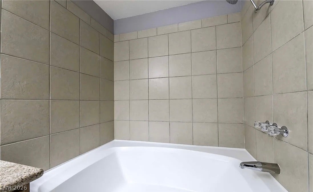 2700 N Rainbow Boulevard, #2137, Las Vegas, NV 89108 Floor-to-ceiling tiles surround a soaking tub equipped with chrome fixtures.