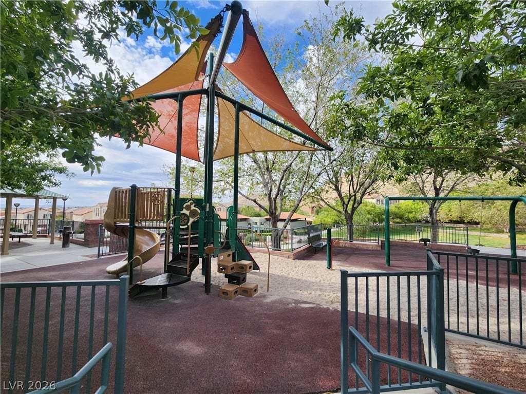 10549 Gibbous Moon Drive, Las Vegas, NV 89129 Mature trees shade a community playground equipped with modern structures and safety fencing.