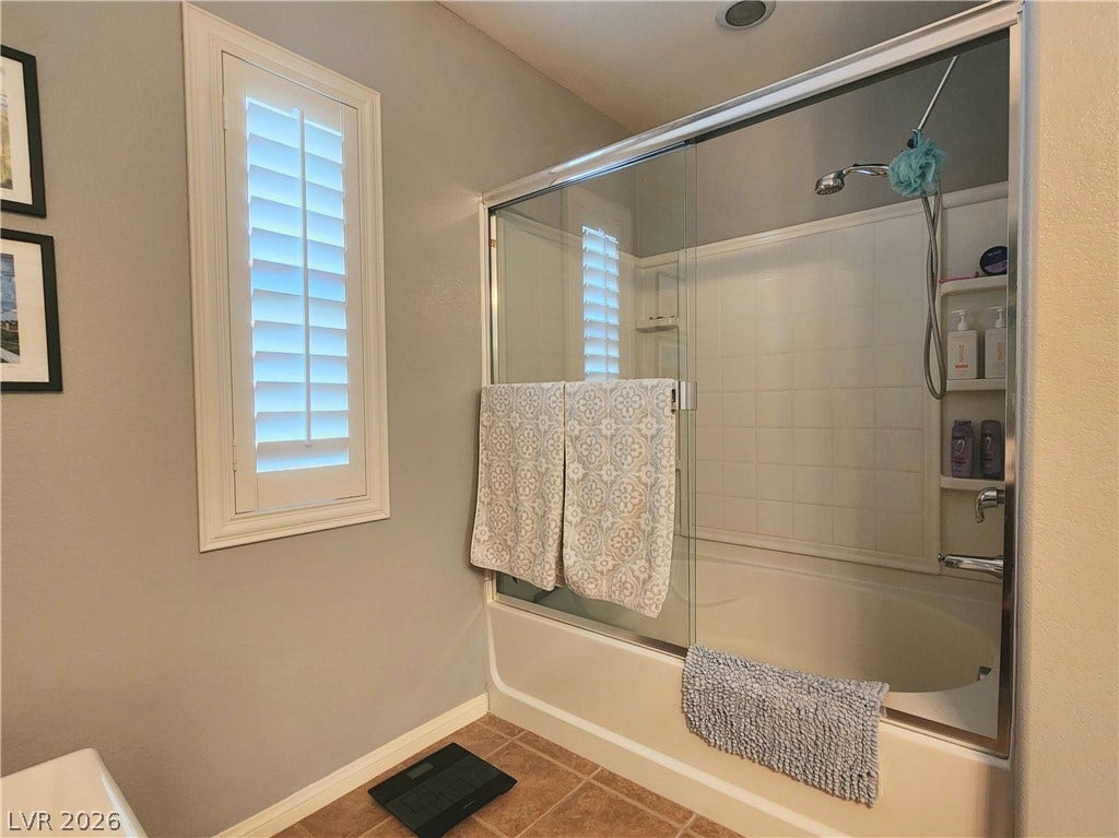 10549 Gibbous Moon Drive, Las Vegas, NV 89129 Tile flooring and plantation shutters complement the tub with sliding glass doors.