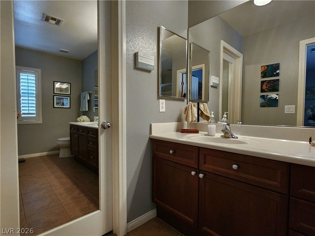 10549 Gibbous Moon Drive, Las Vegas, NV 89129 A spacious vanity area with dark wood cabinetry connects directly to the private restroom.