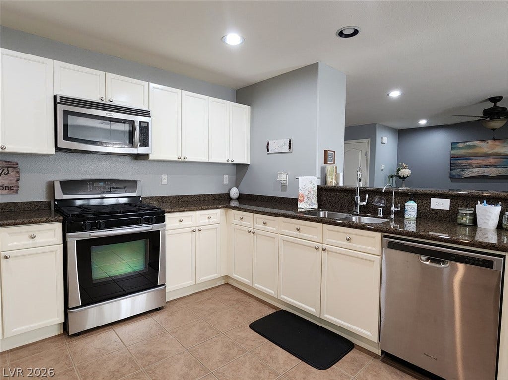 10549 Gibbous Moon Drive, Las Vegas, NV 89129 Tiled flooring and dark granite countertops accent this functional culinary space with an open-concept design.
