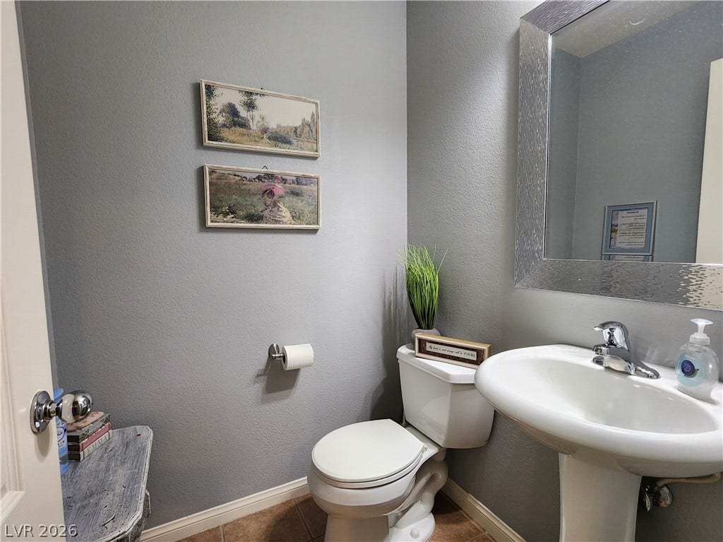 10549 Gibbous Moon Drive, Las Vegas, NV 89129 Textured gray walls and a classic pedestal sink define this cozy downstairs half bath.