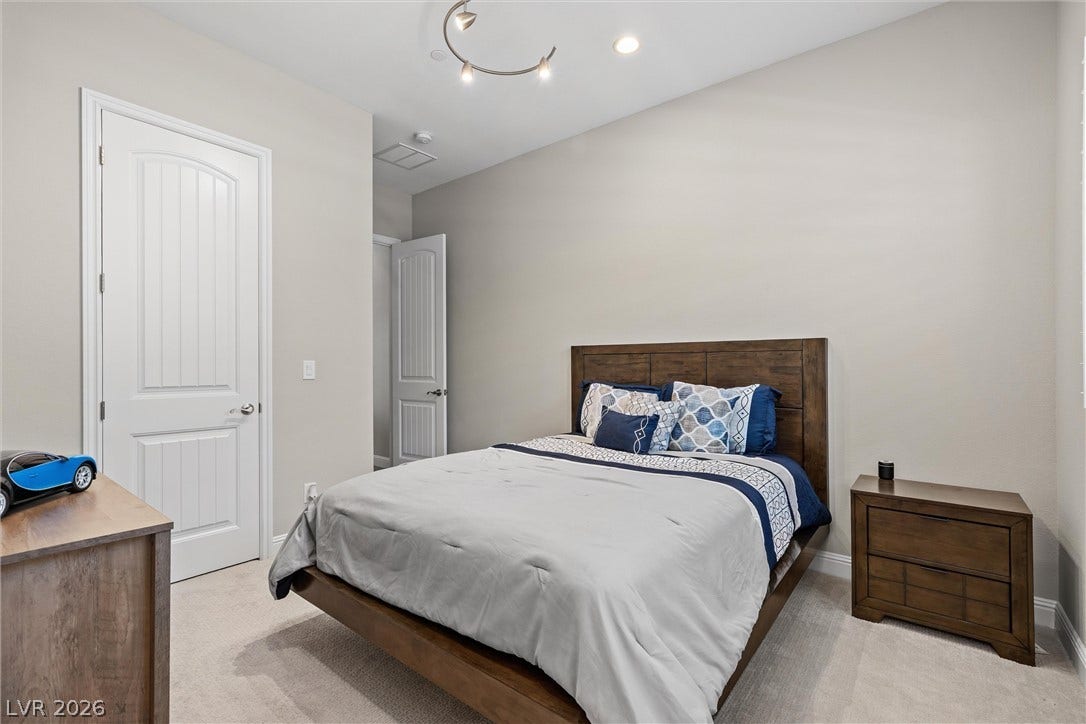 3382 Spring Rock Avenue, Henderson, NV 89044 A quiet bedroom offers soft carpeting underfoot alongside clean architectural lines and neutral walls.