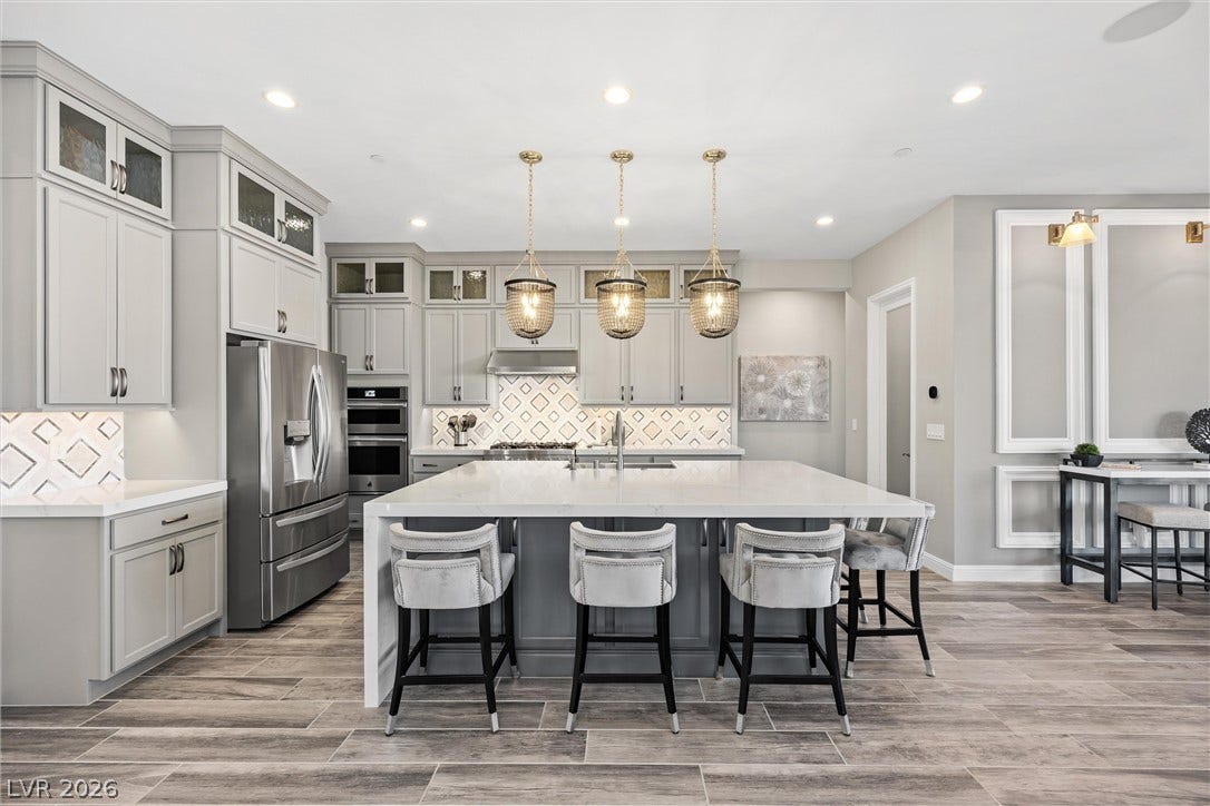 3382 Spring Rock Avenue, Henderson, NV 89044 An expansive kitchen features custom cabinetry, premium stone countertops, and durable wood-look tile flooring.