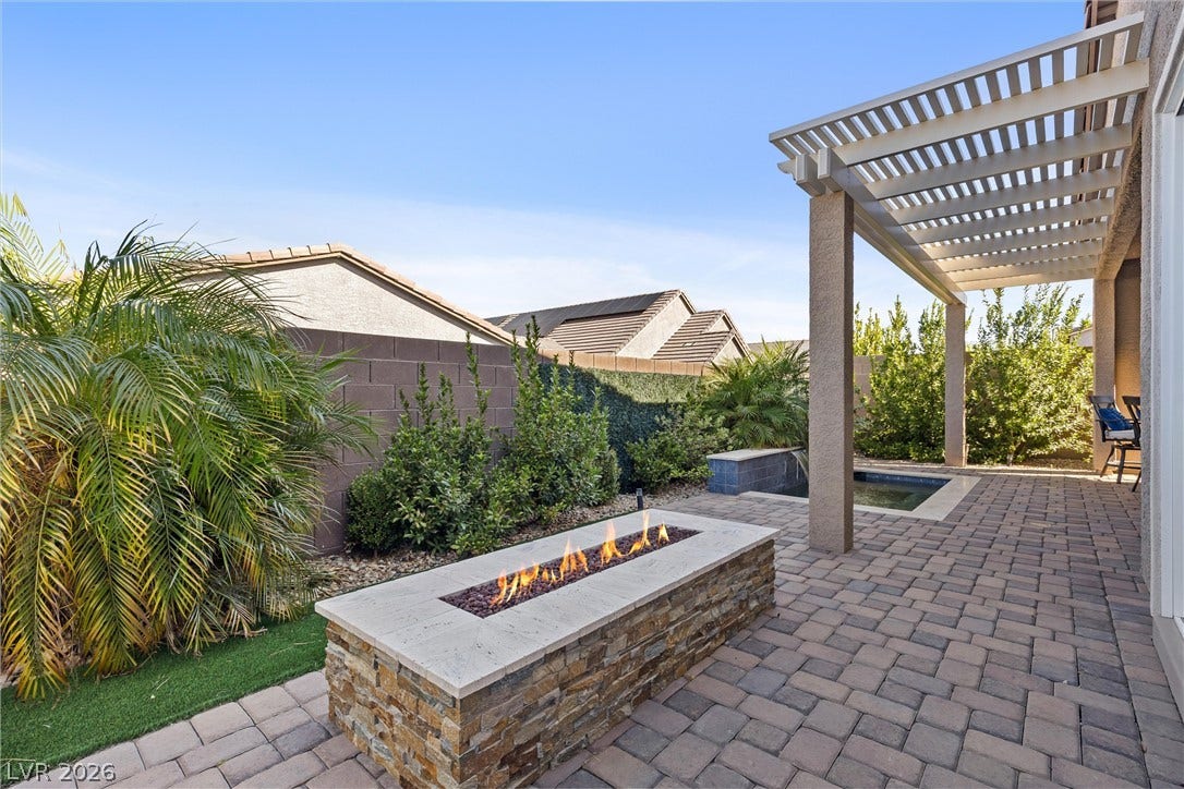 3382 Spring Rock Avenue, Henderson, NV 89044 An inviting stone fire pit accents the paved patio beneath a classic wood pergola.