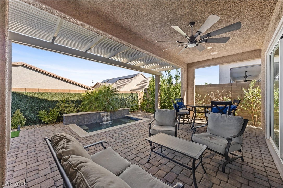 3382 Spring Rock Avenue, Henderson, NV 89044 A covered patio with paved flooring overlooks a private pool with a waterfall feature.