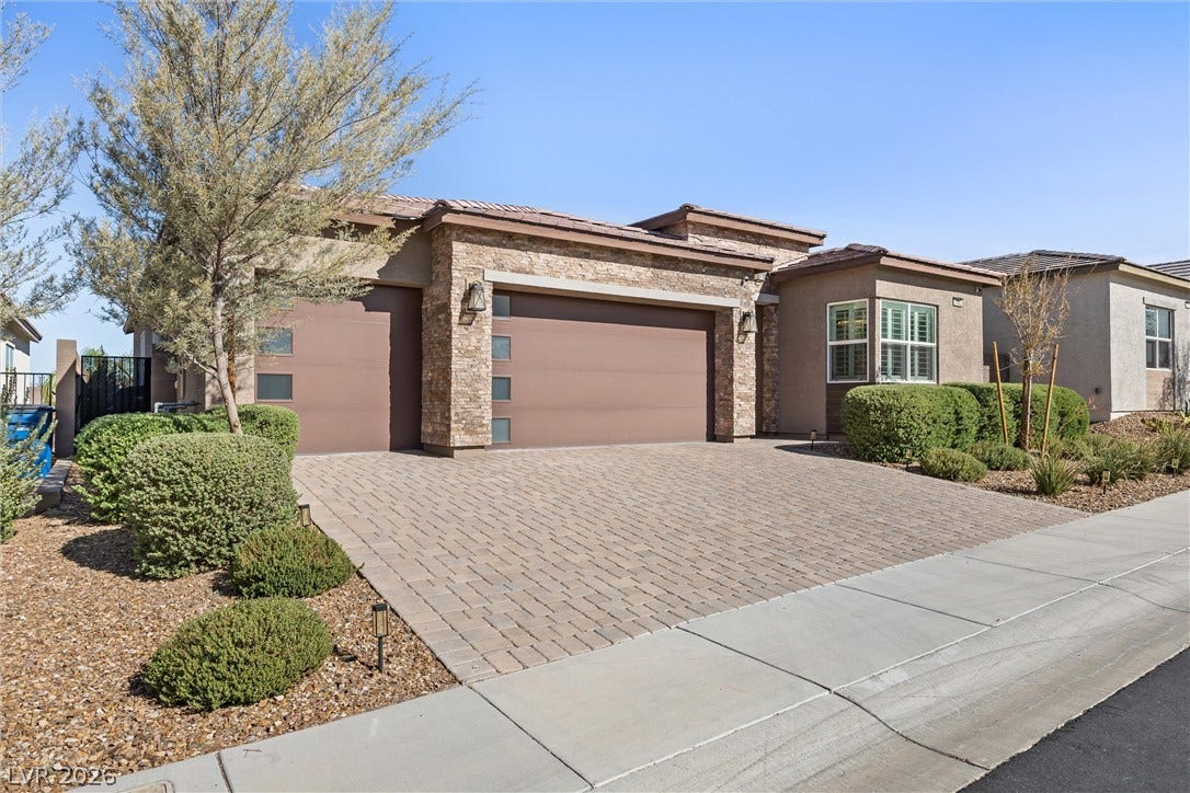 3382 Spring Rock Avenue, Henderson, NV 89044 An inviting stone-accented facade showcases a spacious paver driveway leading to modern garage bays.