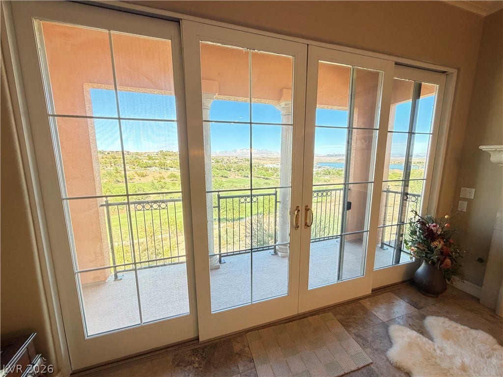 12 Via Visione, #204, Henderson, NV 89011 Sliding glass doors frame sweeping views of the surrounding hills, water, and golf course.