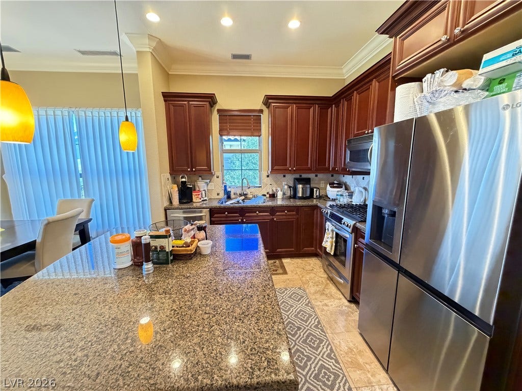 12 Via Visione, #204, Henderson, NV 89011 Rich wood cabinetry and polished granite counters anchor this well-appointed kitchen workspace.