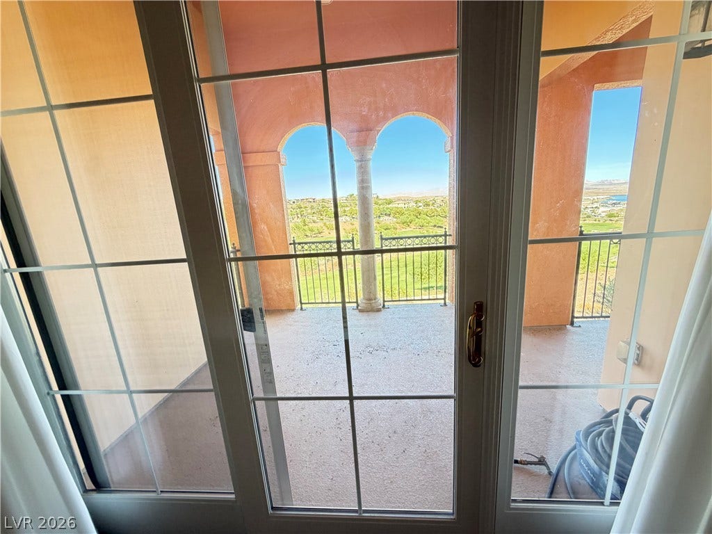 12 Via Visione, #204, Henderson, NV 89011 Glass sliding doors open to a private balcony framed by elegant arched stone columns.