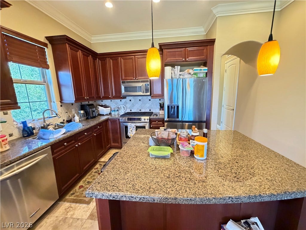 12 Via Visione, #204, Henderson, NV 89011 Rich wood cabinetry paired with granite countertops anchors this functional kitchen design.