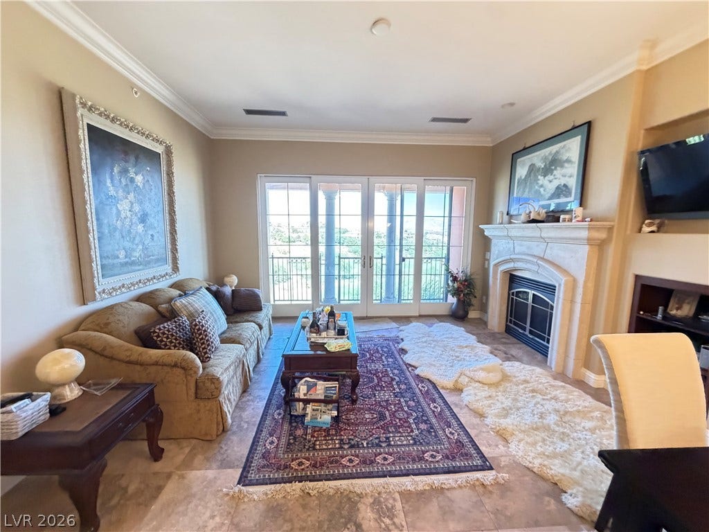 12 Via Visione, #204, Henderson, NV 89011 An elegant stone fireplace anchors this living space accented by crown molding and tile floors.