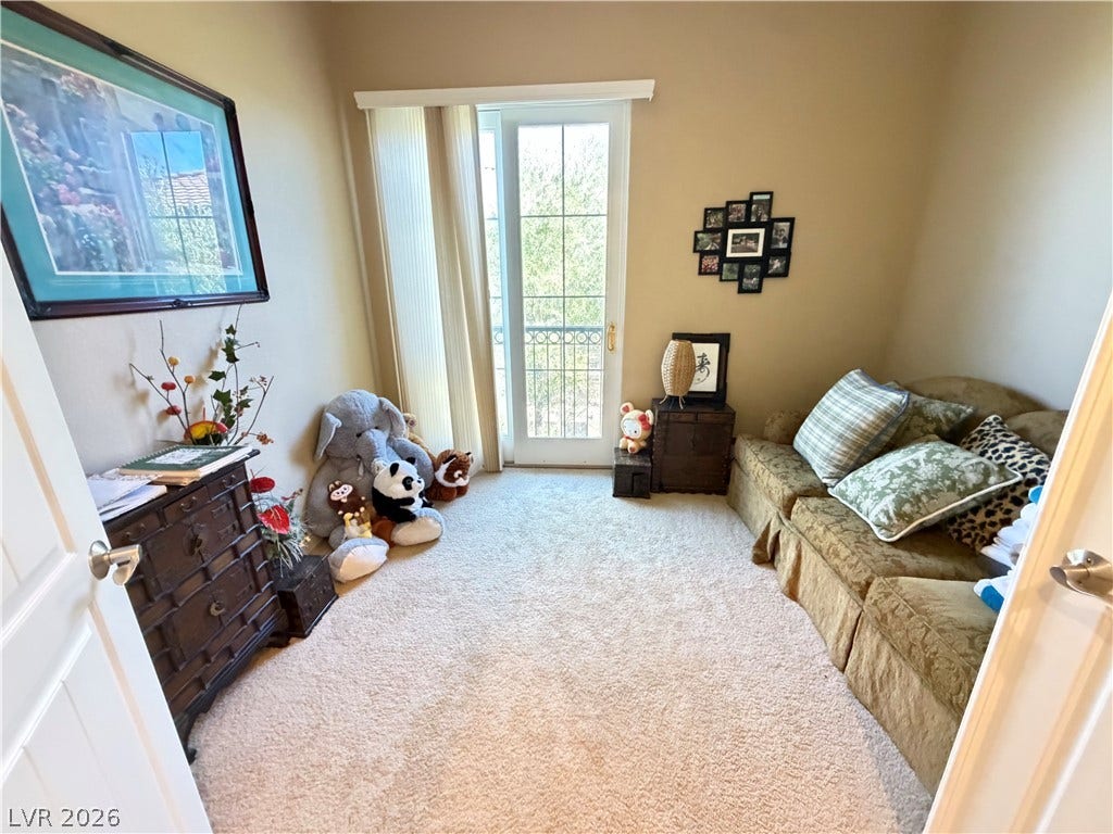 12 Via Visione, #204, Henderson, NV 89011 Glass sliding doors open to the outdoors, filling the carpeted room with natural light.