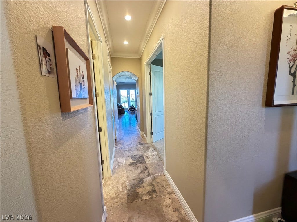 12 Via Visione, #204, Henderson, NV 89011 Stone tile floors and classic crown molding guide the way through this inviting hallway.