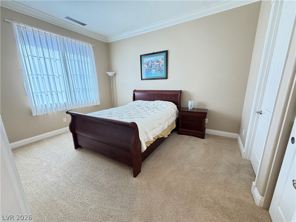 12 Via Visione, #204, Henderson, NV 89011 Crown molding highlights the ceiling of a comfortable bedroom featuring plush carpet and ample windows.