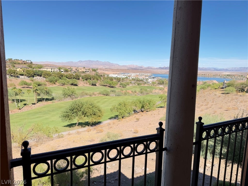 12 Via Visione, #204, Henderson, NV 89011 A private covered balcony frames scenic golf course, lake, and mountain views under blue skies.