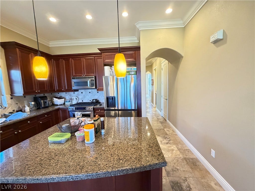 12 Via Visione, #204, Henderson, NV 89011 Rich wood cabinetry and premium stone countertops define this well-appointed kitchen space.