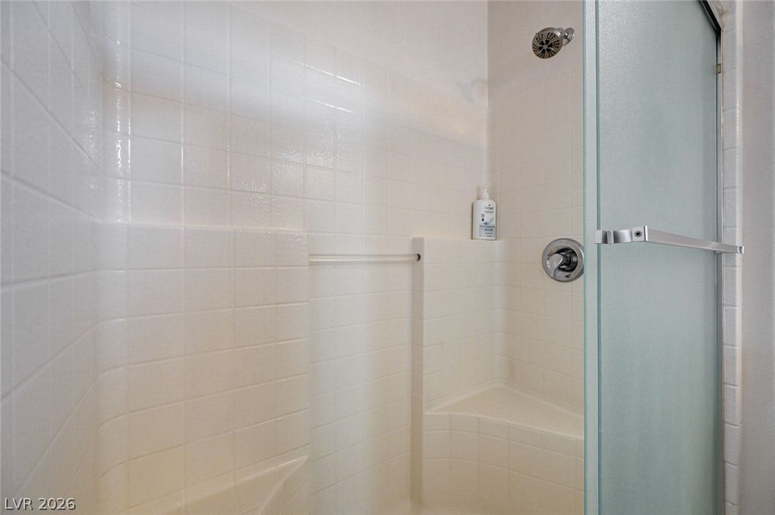 2851 Sapphire Desert Drive, Henderson, NV 89052 Tiled walk-in shower features built-in seating behind a frosted glass door.